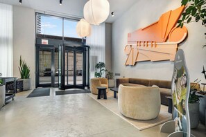 A modern lobby with a revolving door, seating area, and a large abstract wall art piece. - South Loop Rooftop With In and Out Parking 6 (Chicago)
