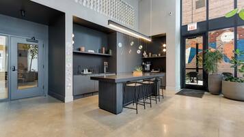 Cozinha moderna com ilha central, banquetas e um mezanino com parede estampada.