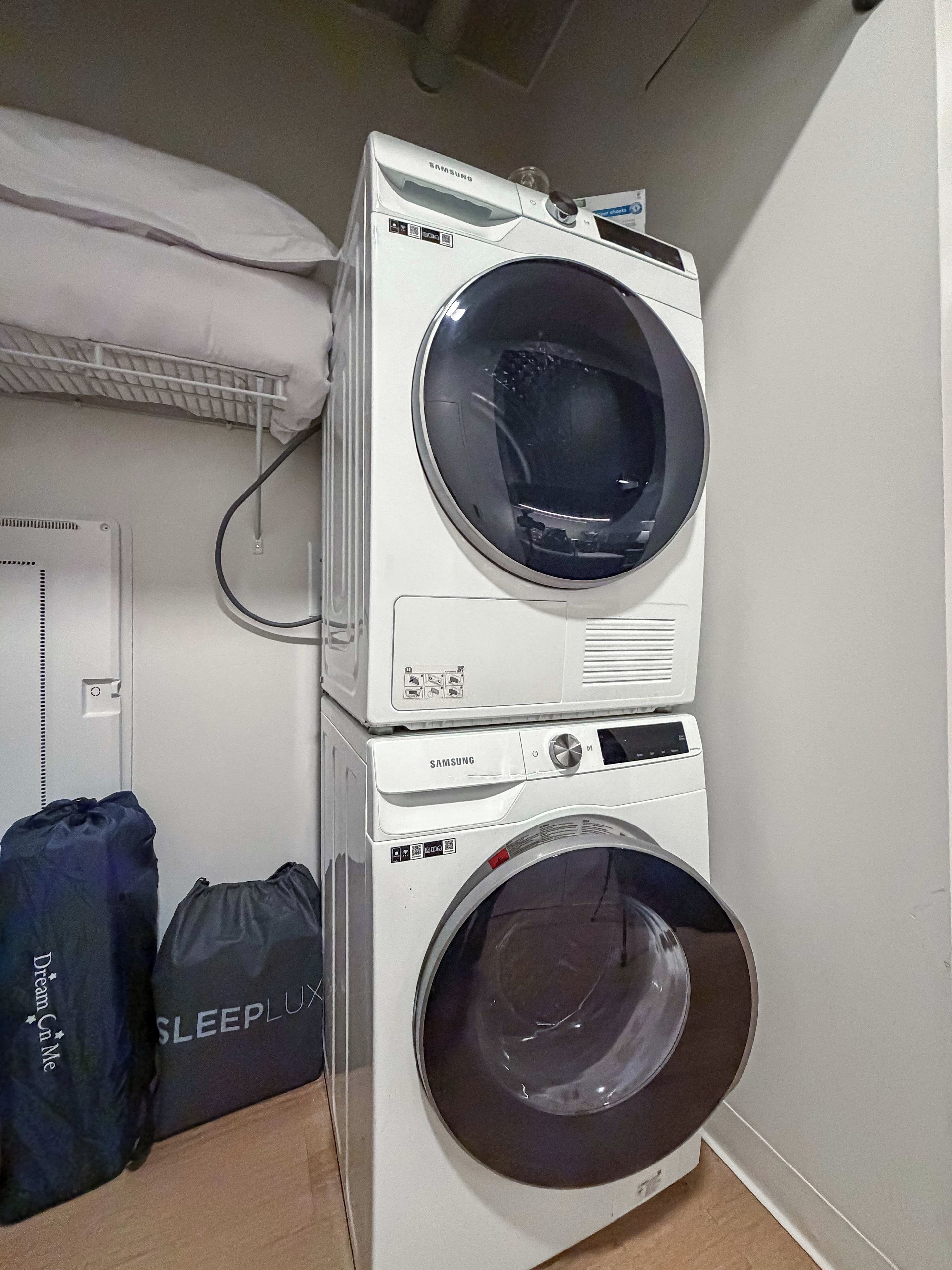 Máquina de lavar e secar empilhada, com acabamento branco, painel de controle e cabo de alimentação.