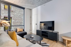 Een moderne woonkamer met een bank, salontafel en een flatscreen televisie aan de wand.