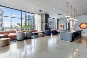 Um interior moderno com área de estar, bar e janelas amplas com vista para a cidade.
