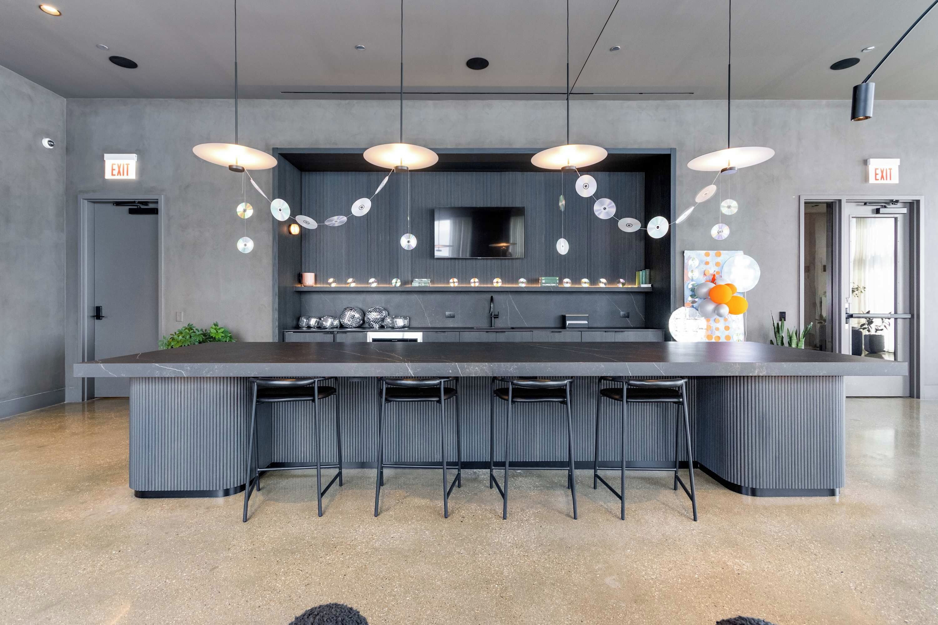 Cozinha moderna com ilha central, banquetas e iluminação pendente.