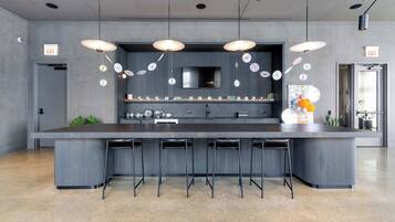 Cozinha moderna com ilha central, banquetas e iluminação pendente.