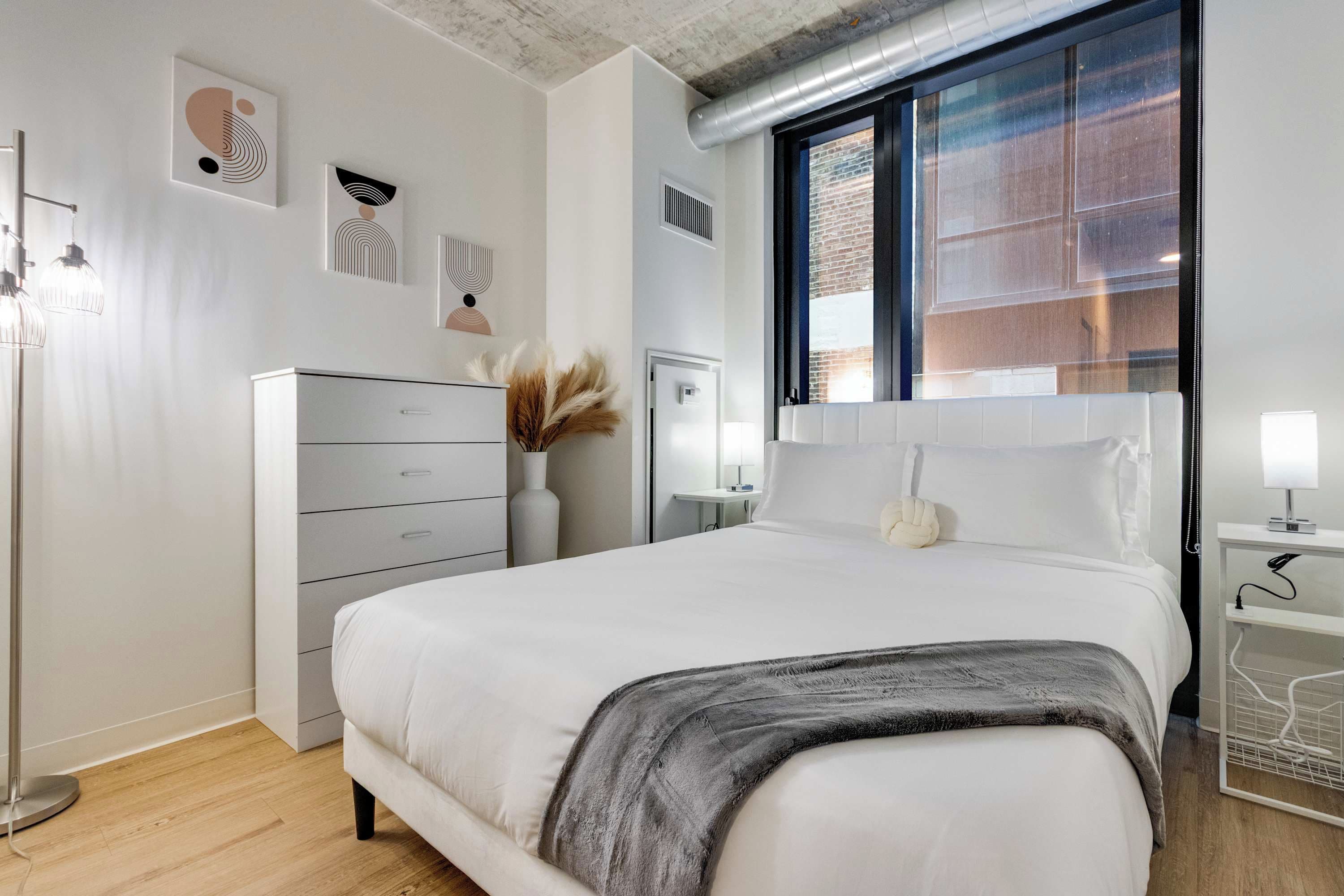 Quarto moderno com cama, mesa de cabeceira e abajur.