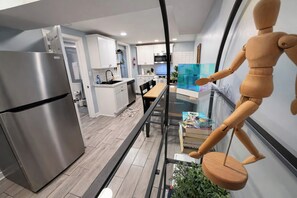 Eine moderne Küche mit einem Edelstahl-Kühlschrank, weißen Schränken und einem Holztisch.