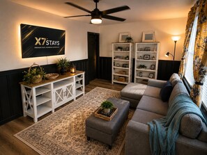 A modern living room with a sectional sofa, a white entertainment unit, and a ceiling fan. - Georgetown Cozy Duo - Entire Duplex (Georgetown)