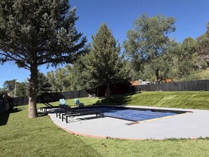 A backyard with a swimming pool, a covered patio area, and a fenced yard. - Mountain Retreat w/ Pool & Mountain Views (Carbondale)