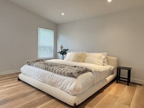 Une chambre à coucher avec un grand lit, une petite table de chevet et une fenêtre avec des stores.