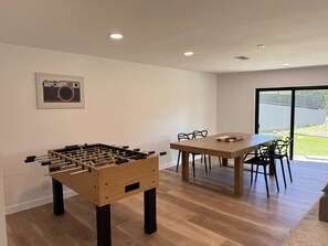 Une pièce moderne avec un baby-foot en bois et une table à manger avec des chaises.