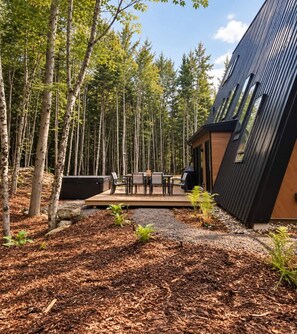 Un edificio moderno con terraza y zona de estar exterior rodeado de un bosque.