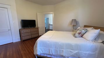 A bedroom with a bed, dresser, television, and lamp.
