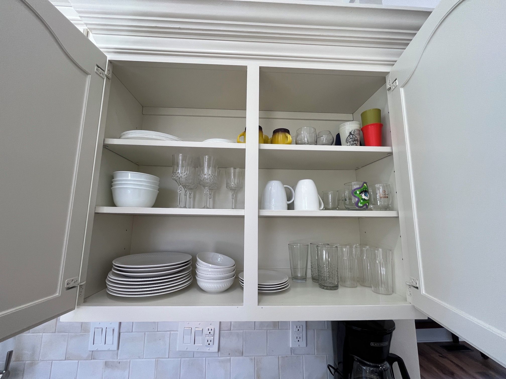 Un meuble de cuisine doté de plusieurs étagères contenant des assiettes, des bols, des verres et une machine à café.