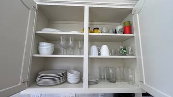 Un meuble de cuisine doté de plusieurs étagères contenant des assiettes, des bols, des verres et une machine à café.