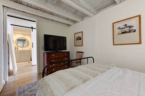A bedroom with a bed, a dresser, a television, and framed pictures on the wall. - Le Tomahawk - Potton en Estrie (Potton)