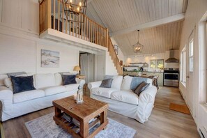 A spacious living area with two white sofas, a wooden coffee table, and a staircase leading to an upper level. - Le Tomahawk - Potton en Estrie (Potton)