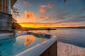 A hot tub on a wooden deck with a view of a sunset over a body of water. - Le Tomahawk - Potton en Estrie (Potton)