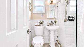Un baño con inodoro, lavamanos, ducha y ventana.