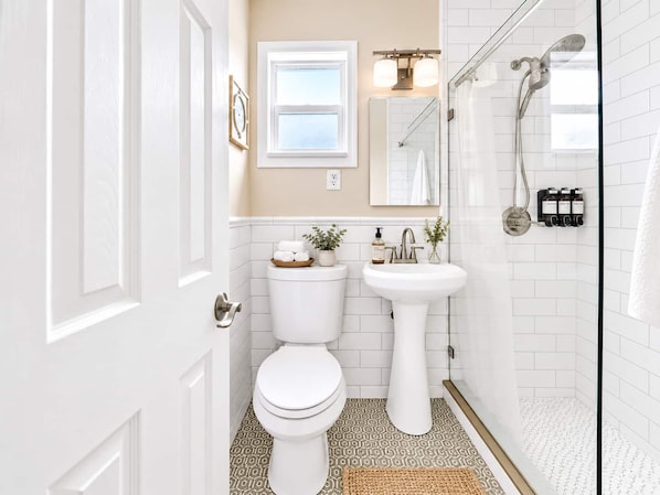 Une salle de bain équipée de toilettes, d’un lavabo, d’une douche et d’une fenêtre.