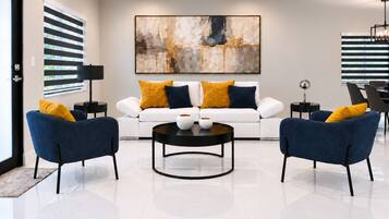 A modern living room with a white sofa, two blue armchairs, a black coffee table, and a large abstract painting on the wall.