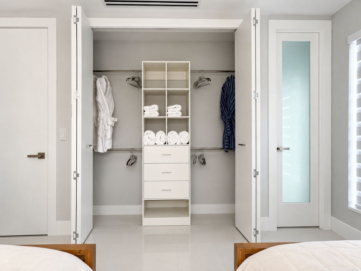 Un dormitorio moderno con armario empotrado, cama y baño con puertas de cristal satinado.