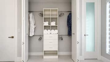 Un dormitorio moderno con armario empotrado, cama y baño con puertas de cristal satinado.