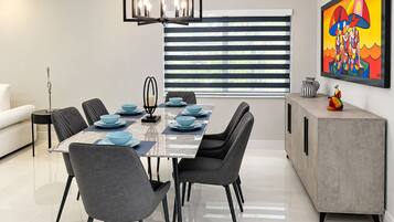Un comedor moderno con una mesa rectangular, sillas negras y una lámpara de techo contemporánea.