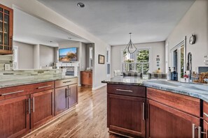 A spacious kitchen with wooden cabinets, a large island, and a view of the outdoors. - Keppel Cove | Saugatuck • Hot Tub • Rec Room! (Saugatuck)