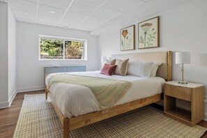Een slaapkamer met een bed, nachtkastjes, een raam en kunst aan de muur.
