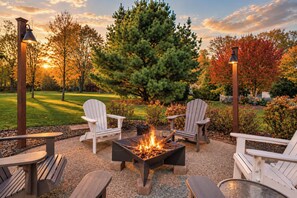 An outdoor seating area with Adirondack chairs, a fire pit, and a view of a golf course. - Keppel Cove | Saugatuck • Hot Tub • Rec Room! (Saugatuck)
