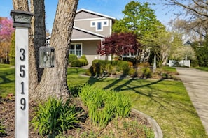 A residential house with a number sign, a tree, and a well-maintained lawn. - Keppel Cove | Saugatuck • Hot Tub • Rec Room! (Saugatuck)