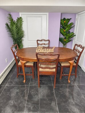 A dining table with four chairs, a 'Blessed' sign, and two potted plants.