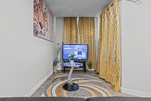 A modern living room with a flat-screen TV, a glass coffee table, and decorative plants. - Beautiful King Size Bedroom BM Unit Close to Downtown Edm,Fast Wifi, Private Ent (Edmonton)