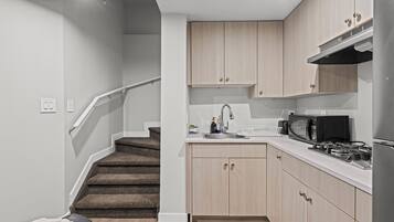 A compact kitchen with a microwave, stove, and sink.