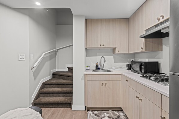 A compact kitchen with a microwave, stove, and sink.