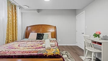 A bedroom with a wooden bed, a desk, a chair, and a potted plant.