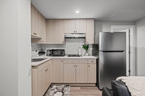 A compact kitchen with light wood cabinets, a stainless steel refrigerator, a microwave, and a gas stove. - Beautiful King Size Bedroom BM Unit Close to Downtown Edm,Fast Wifi, Private Ent (Edmonton)