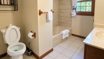 A bathroom with a toilet, a bathtub, and a shower area.