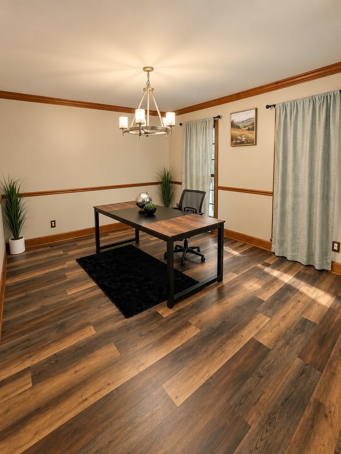 A room with a wooden floor, a table with chairs, a chandelier, a potted plant, and a painting on the wall.