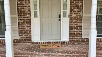 A brick house with a white front door, a doormat, and a small porch area.