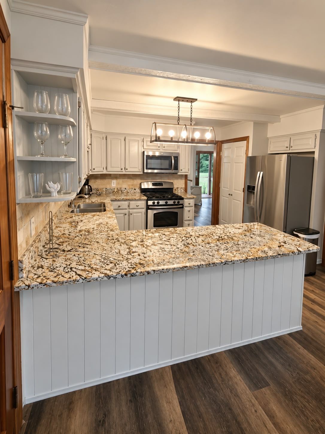 A kitchen with white cabinetry, a granite countertop, stainless steel appliances, and a hanging light fixture.