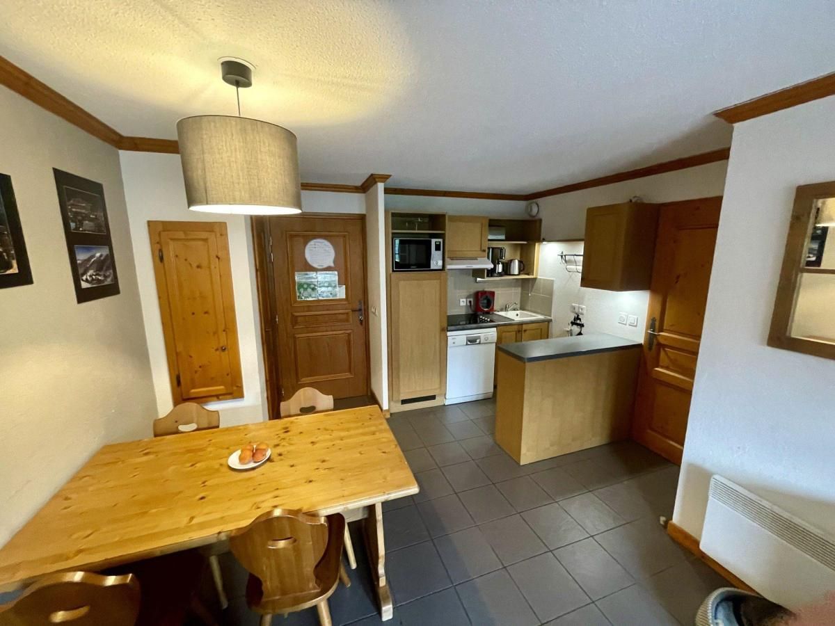 A compact kitchen with a dining table, wooden cabinets, and a microwave.