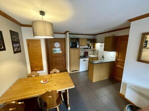 A compact kitchen with a dining table, wooden cabinets, and a microwave. - 50m from ski slopes, 3rd floor, swimming pool, sauna, ski locker, 40m², Valloire (Valloire)