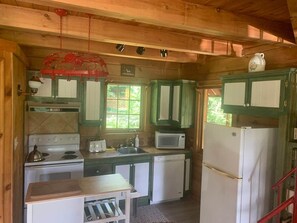 Una cucina compatta con piano cottura, forno a microonde, lavello e frigorifero.