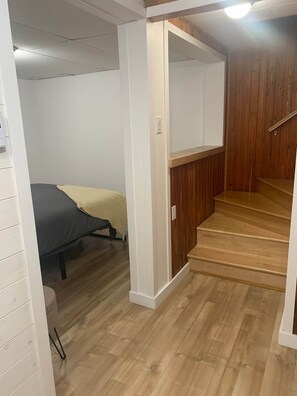 A room with a bed, a wooden staircase, and a white wall. - Maison du Lac (Témiscouata-sur-le-Lac)