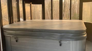 A hot tub with a bench and a table in a covered outdoor area.