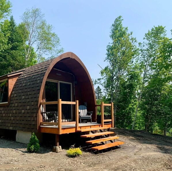 A single-story cabin with a curved roof, a wooden deck, and a small porch.