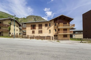 A multi-story building with balconies, a flat roof, and a mountain in the background. - 350m from ski slopes, 1st floor, balcony, tv, ski locker, 30m², Valloire (Valloire)