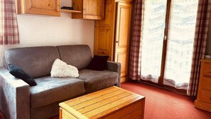 A furnished room with a sofa, a wooden coffee table, and a window with curtains. - 350m from ski slopes, 1st floor, balcony, tv, ski locker, 30m², Valloire (Valloire)