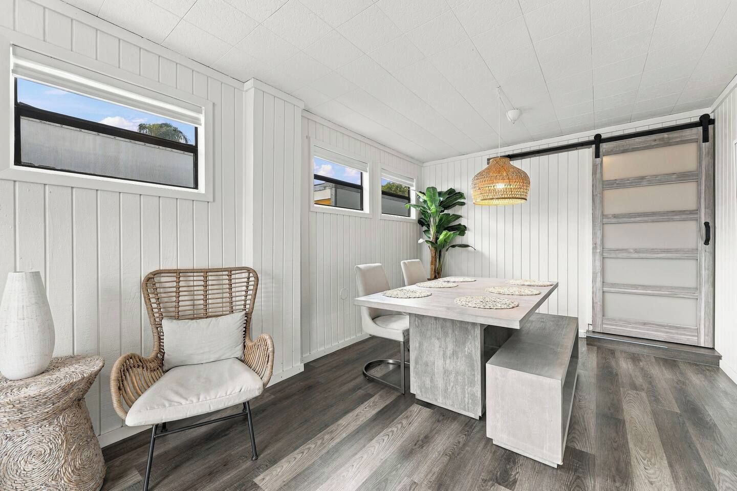 A modern kitchen with a dining table, chairs, and a hanging light fixture.