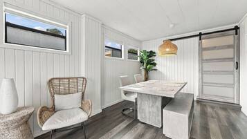 A modern kitchen with a dining table, chairs, and a hanging light fixture.